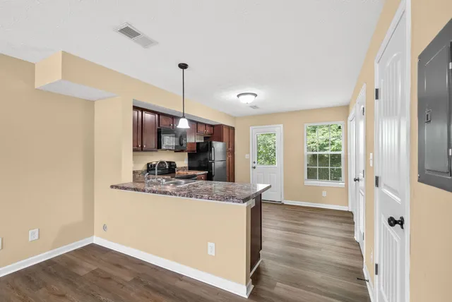 a kitchen with stainless steel appliances granite countertop a sink a refrigerator and a wooden floor