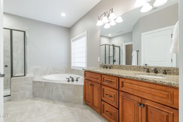 a spacious bathroom with a granite countertop double vanity sink a mirror and a bathtub