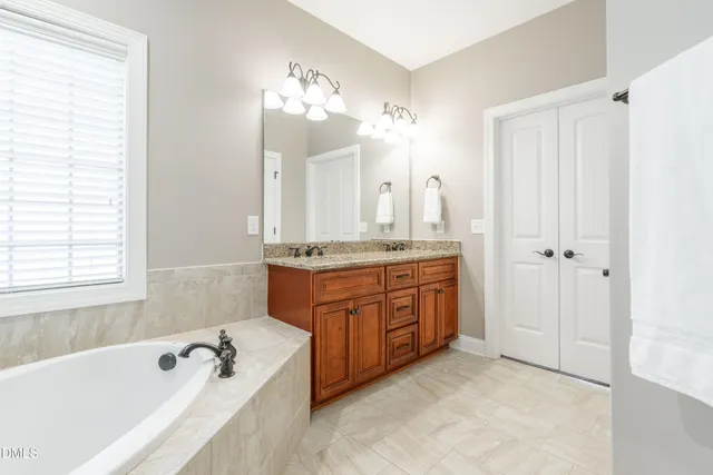 a spacious bathroom with a tub sink and mirror