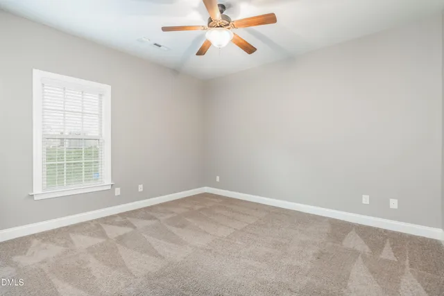 an empty room with windows and fan
