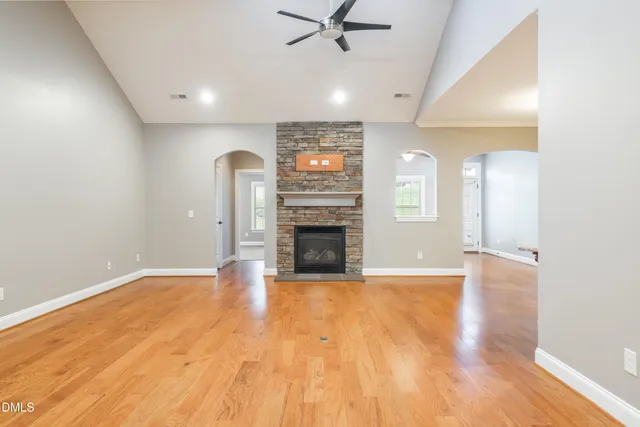 a view of a livingroom with a fireplace a ceiling fan and wooden floor