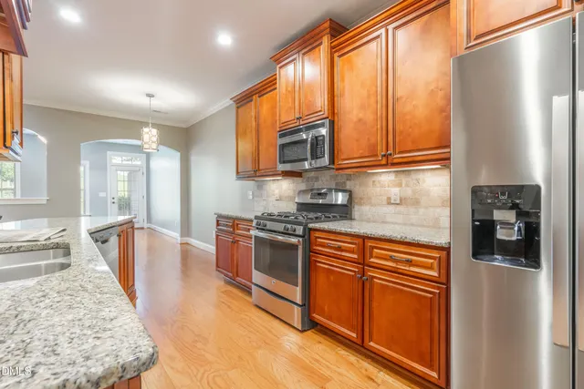 a kitchen with stainless steel appliances granite countertop a refrigerator a stove top oven a sink and dishwasher