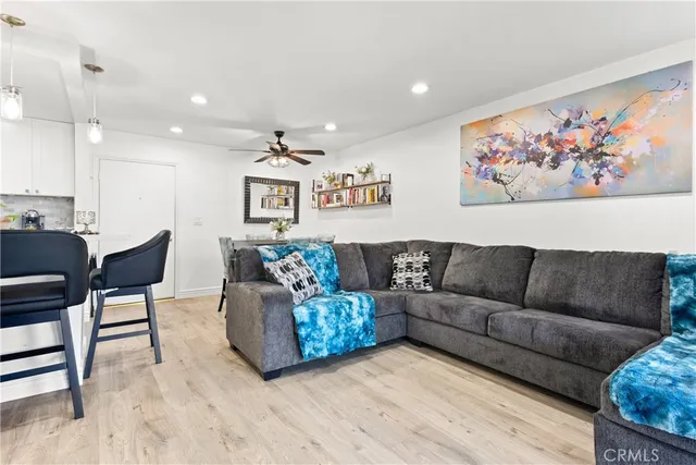 a living room with couches a coffee table and kitchen view with wooden floor