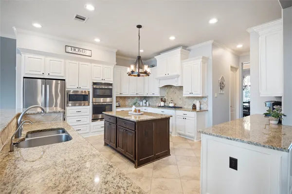 a large kitchen with kitchen island a large counter space a sink stainless steel appliances and cabinets