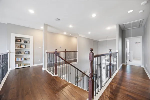 a view of a hallway with wooden floor and windows