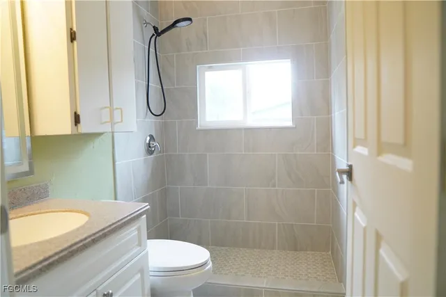 a bathroom with a granite countertop sink a toilet and shower
