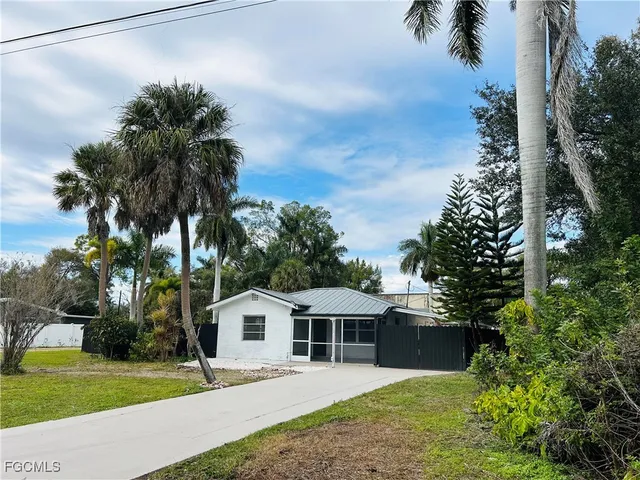 a front view of a house with a garden and trees