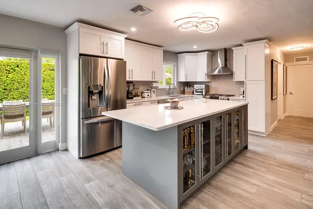 a kitchen with stainless steel appliances a sink a stove a refrigerator cabinets and a large window