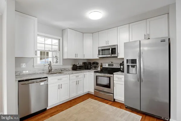 a kitchen with a sink white stainless steel appliances and window