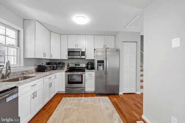 a kitchen with white cabinets stainless steel appliances and window