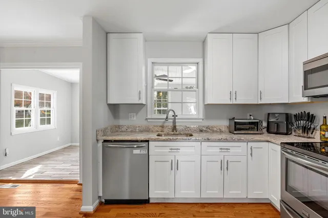 a kitchen with granite countertop a sink stainless steel appliances and cabinets