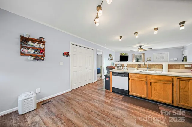 a large white kitchen with a stove a sink dishwasher and a refrigerator with wooden floor