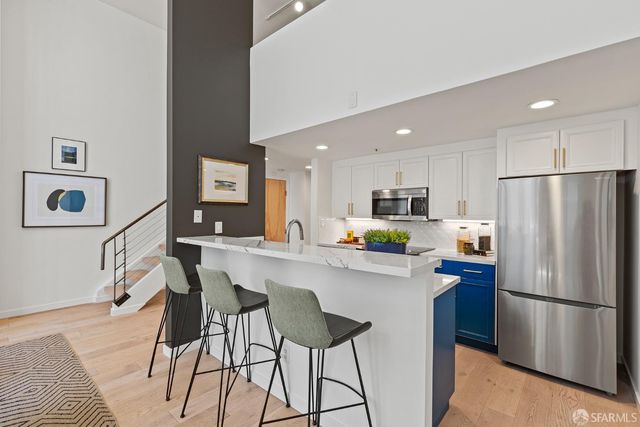 a kitchen with stainless steel appliances a refrigerator a stove a sink a dining table and chairs