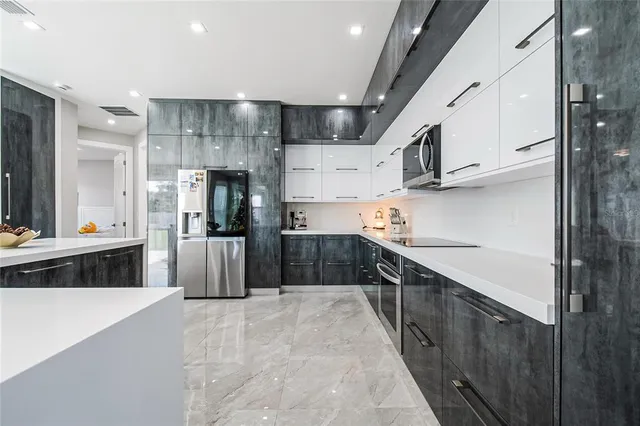 a large kitchen with stainless steel appliances kitchen island a large counter top and wooden cabinets