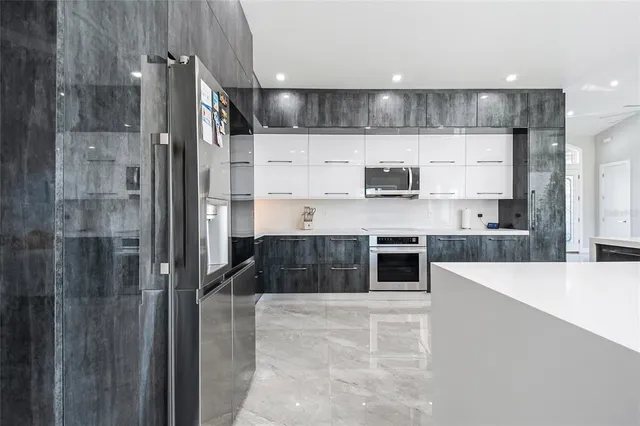 a large kitchen with stainless steel appliances kitchen island granite countertop a refrigerator and a sink