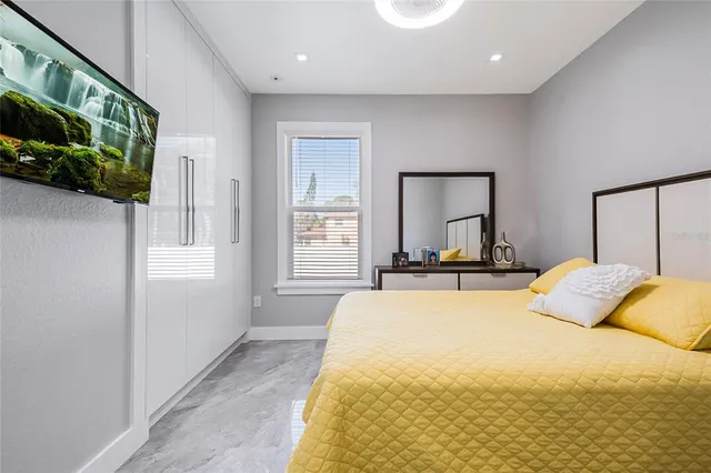 a bedroom with a bed a mirror and windows