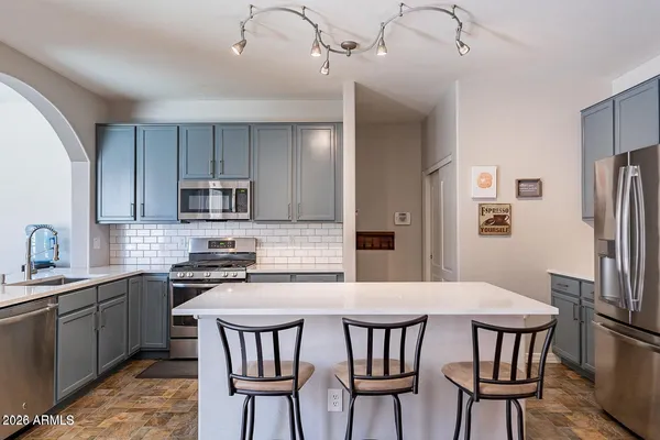 a kitchen with stainless steel appliances a dining table chairs microwave and sink
