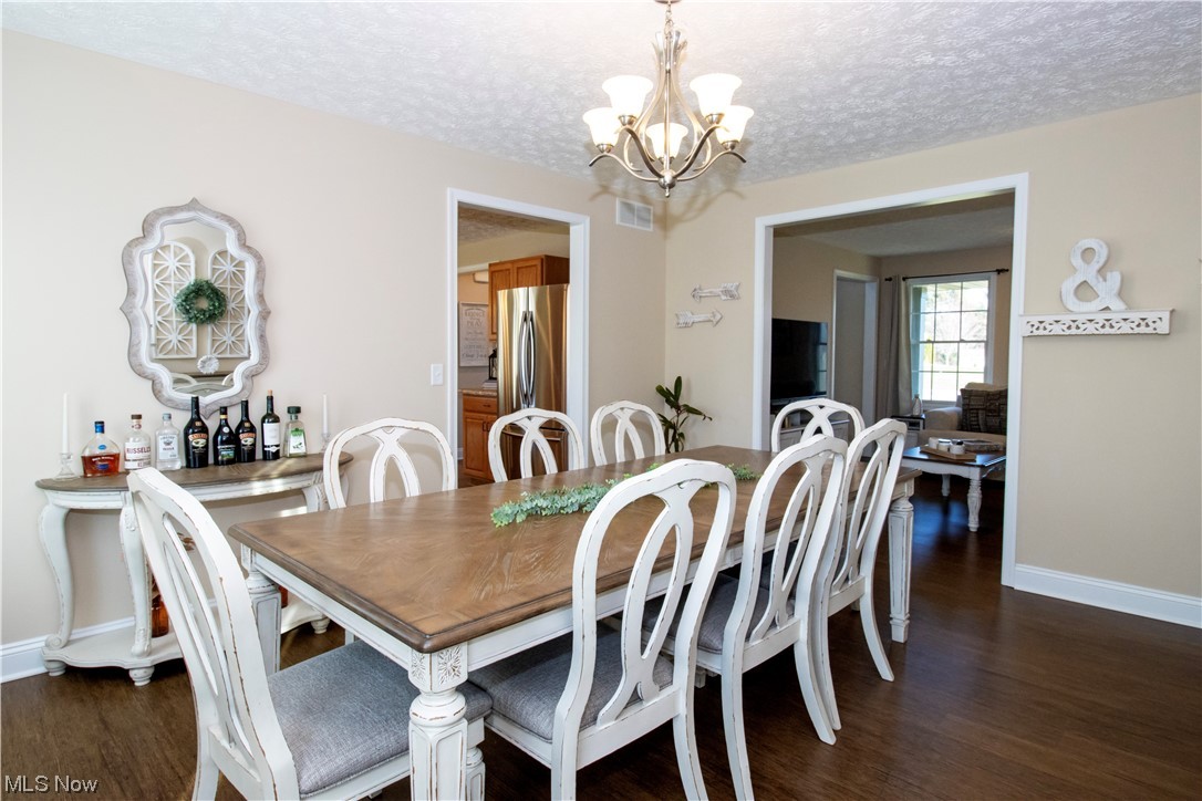 4750 McCauley Road Wooster, OH 44691 - Photo 8 of 37 Dining room featuring an inviting chandelier, dark flooring, and a textured ceiling