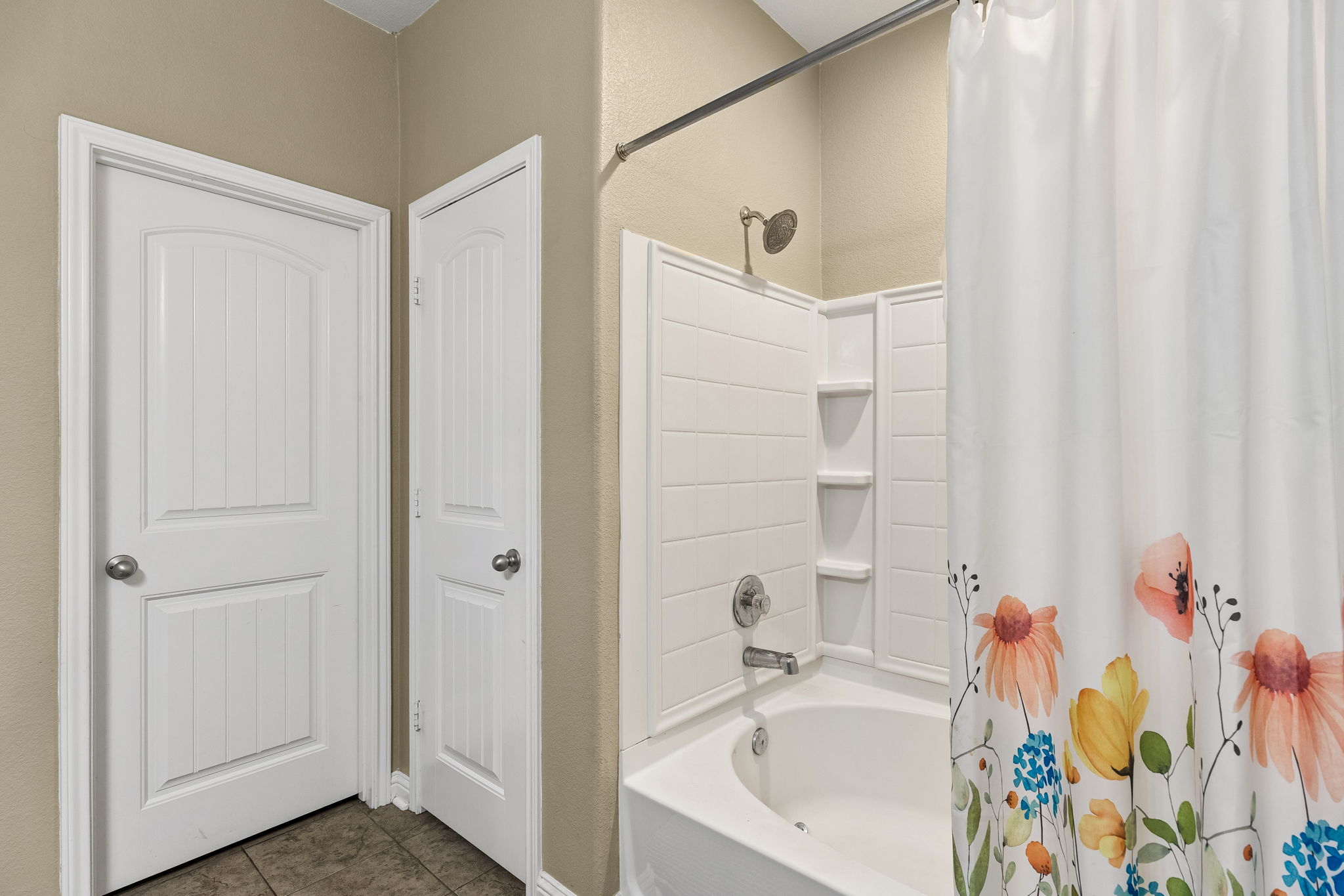 1113 Yellow Iris Road Leander, TX 78641 - Photo 15 of 26 Tiled flooring pairs with a classic shower tub combination featuring integrated shelving.