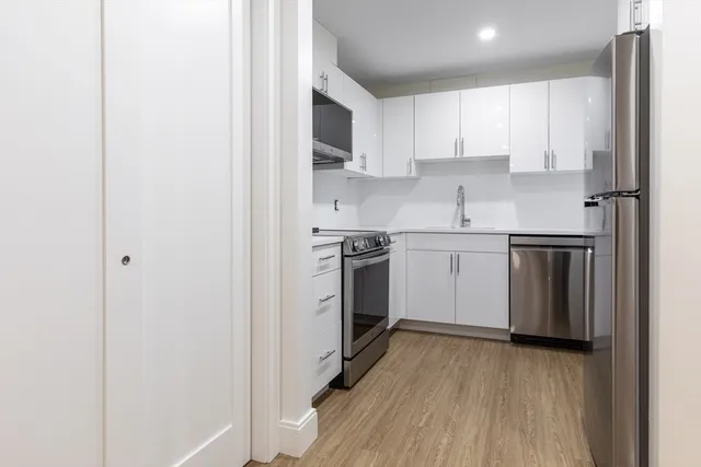 a kitchen with stainless steel appliances granite countertop a stove top oven a sink and white cabinets
