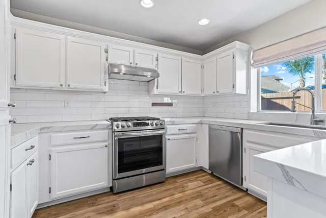 a kitchen with stainless steel appliances granite countertop a stove and white cabinets