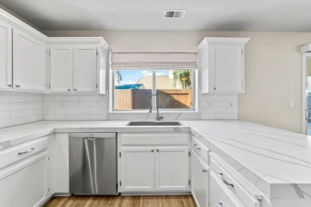 a kitchen with white cabinets and sink