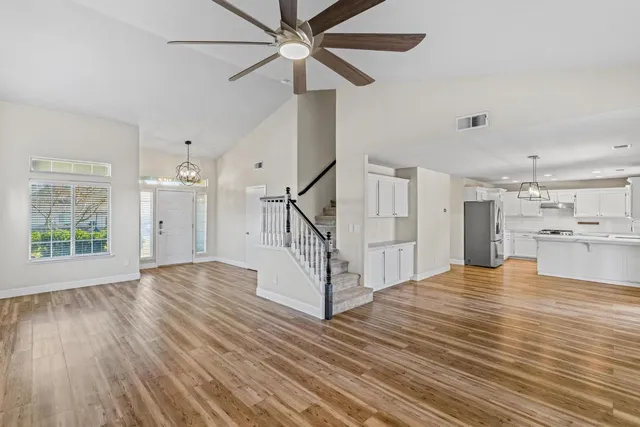 a view of empty room with wooden floor and fan
