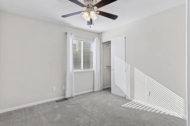 an empty room with windows and fan