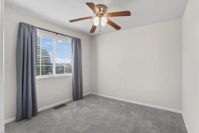 an empty room with a window and a fan