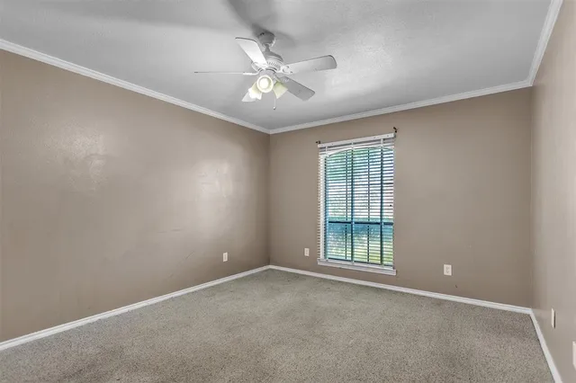 an empty room with a chandelier fan and windows