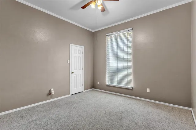 an empty room with chandelier fan and windows