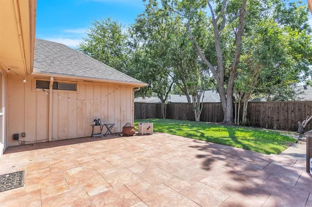 a backyard of a house with wooden fence and large trees