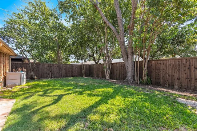 a view of a backyard with large trees and wooden fence