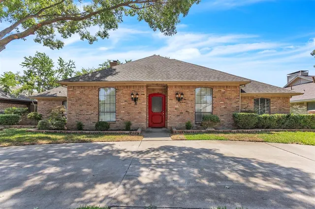 a view of a brick house next to a yard with big trees
