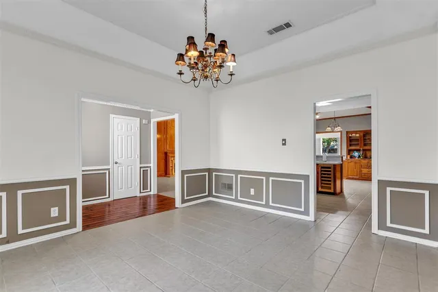 an empty room with chandelier fan and windows