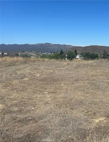 a view of a dry field with mountains in the background