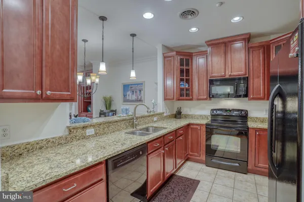 a kitchen with stainless steel appliances granite countertop a sink a stove and a refrigerator