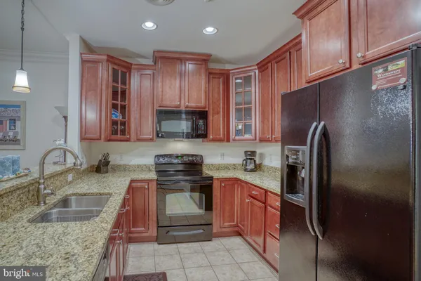 a kitchen with stainless steel appliances granite countertop a sink stove refrigerator and cabinets