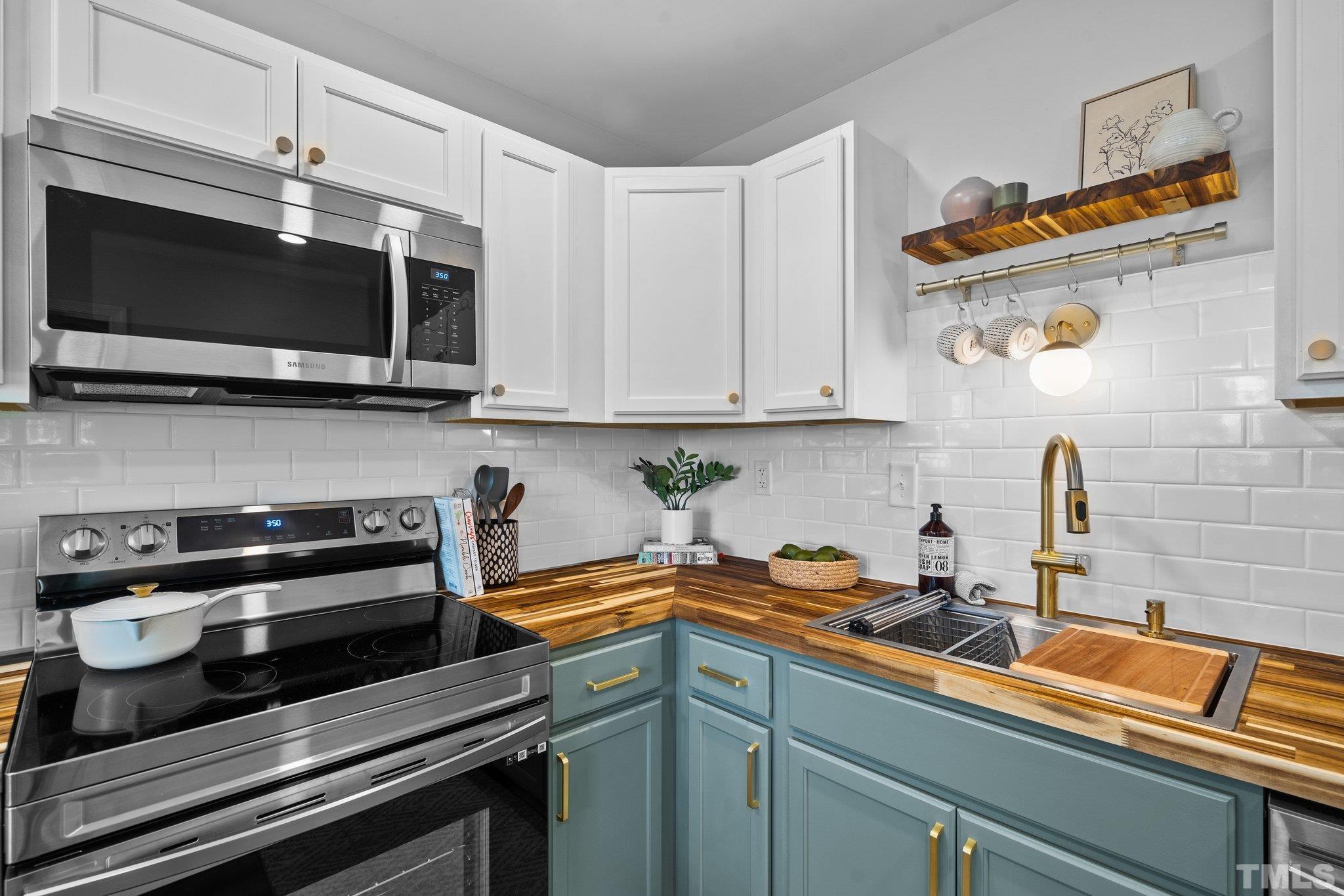 1013 Mockingbird Drive Raleigh, NC 27615 - Photo 12 of 41 a kitchen with stainless steel appliances a stove a microwave and cabinets