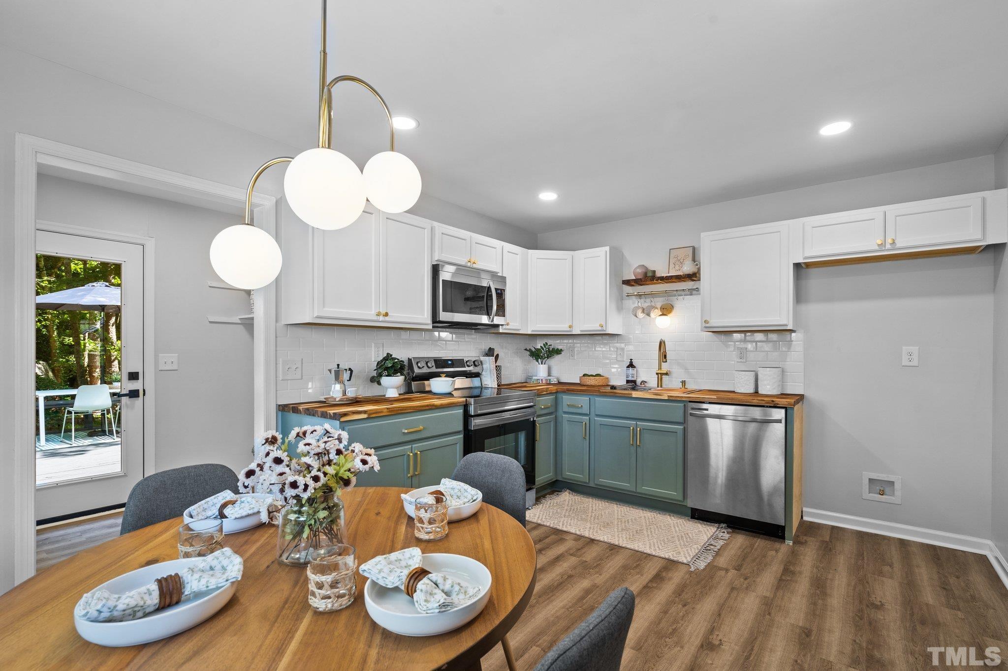 1013 Mockingbird Drive Raleigh, NC 27615 - Photo 15 of 41 a kitchen with stainless steel appliances granite countertop a stove a sink dishwasher a dining table and chairs with wooden floor