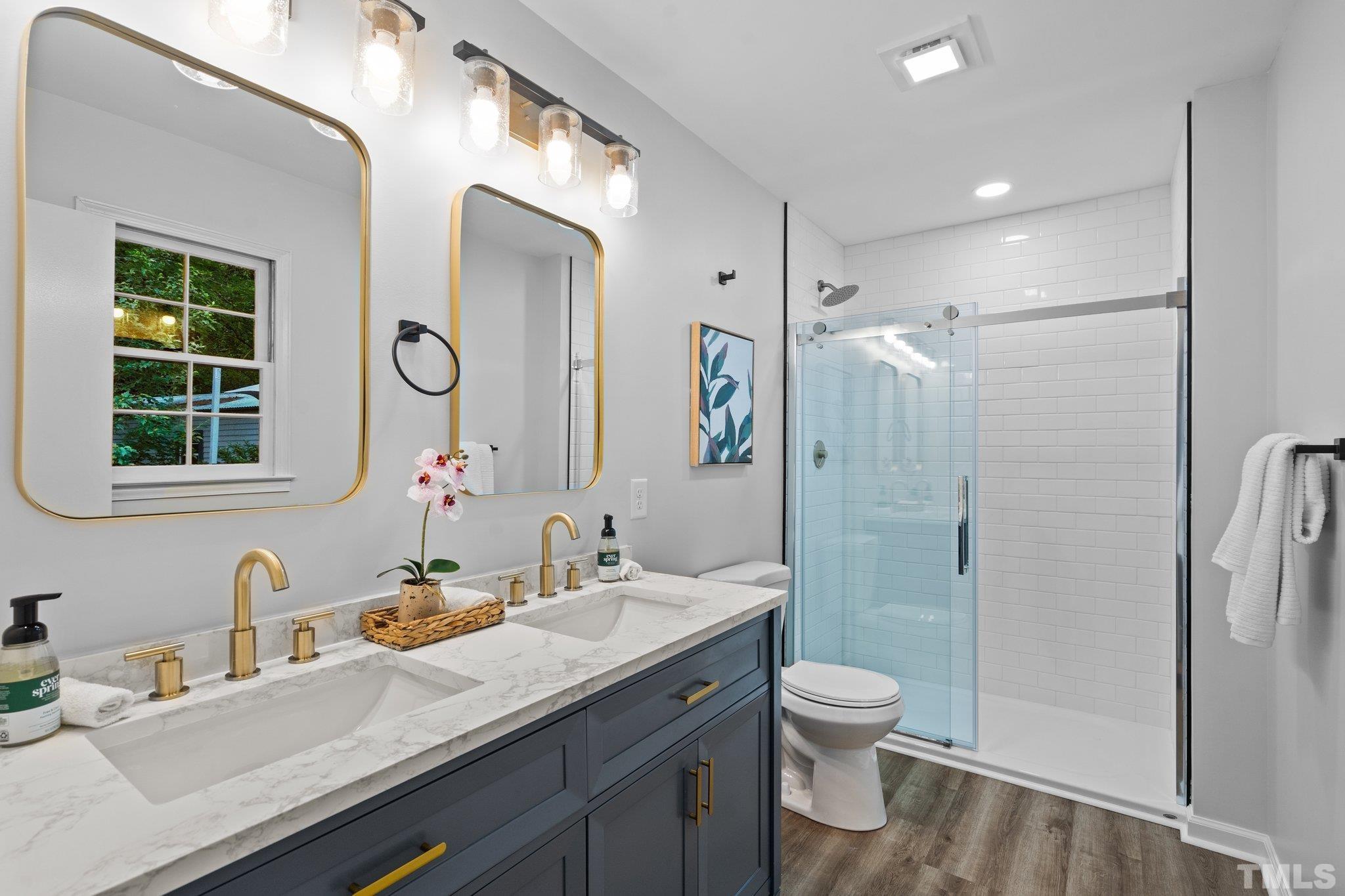 1013 Mockingbird Drive Raleigh, NC 27615 - Photo 27 of 41 a bathroom with a granite countertop sink toilet a large mirror a shower and a mirror