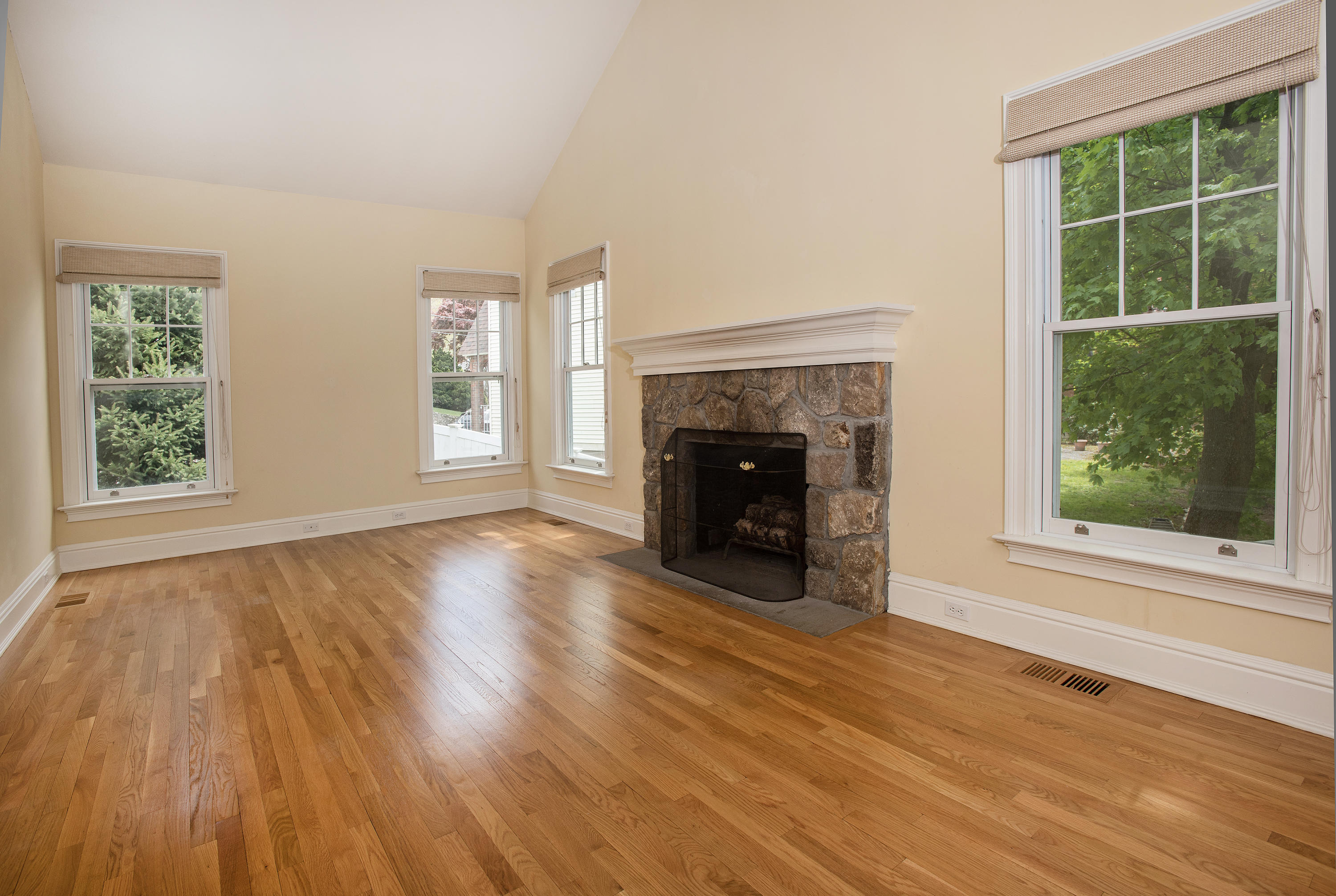 17 Brushy Ridge Road New Canaan, CT 06840 - Photo 11 of 35 an empty room with wooden floor a fireplace and windows