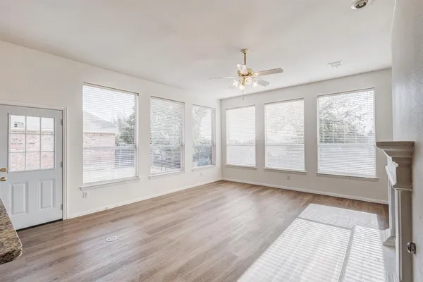 a view of an empty room with a window and wooden floor