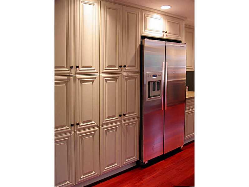 Kitchen. Stainless side-by-side refrigerator on a wall of Maple cabinetry.
