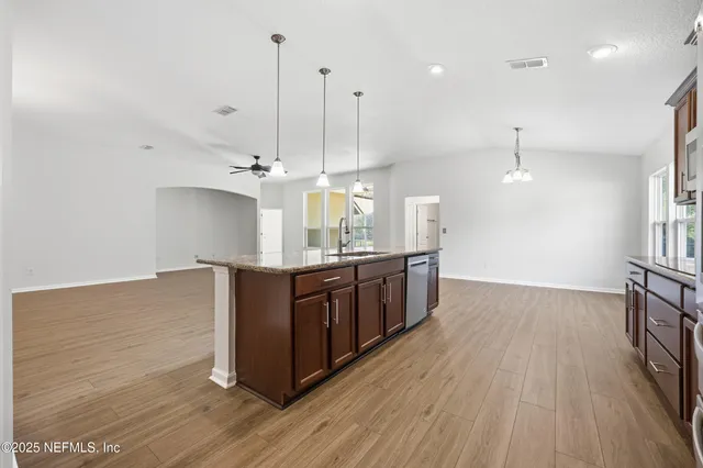 a kitchen with stainless steel appliances granite countertop cabinets a wooden floor and a sink