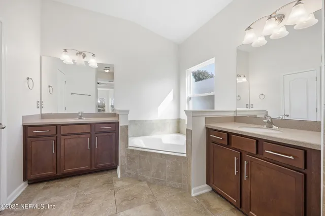 a bathroom with a granite countertop double vanity sink and mirror