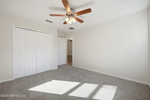 an empty room with ceiling fan and window