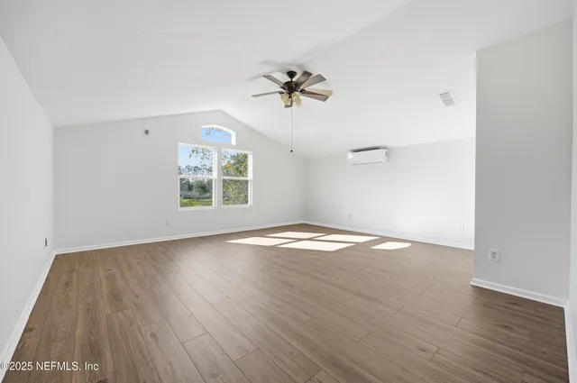 an empty room with wooden floor ceiling fan and windows