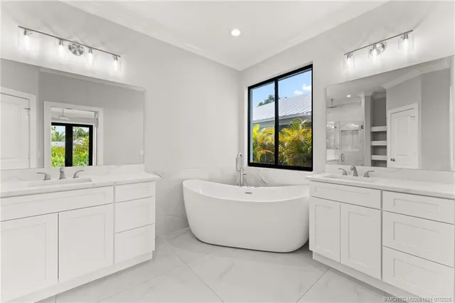 a bathroom with a double vanity sink a large mirror a bathtub and window