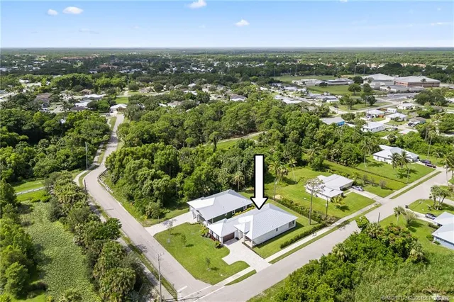 an aerial view of a residential houses with outdoor space and trees